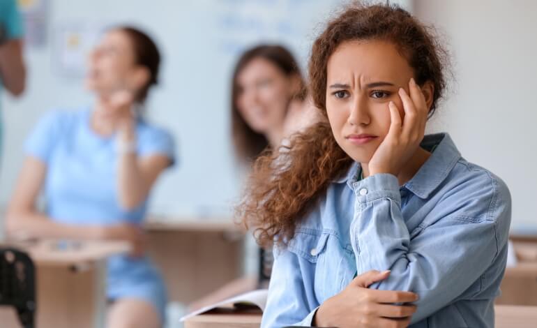 Bullying na escola: imagem mostra aluna com expressão aflita